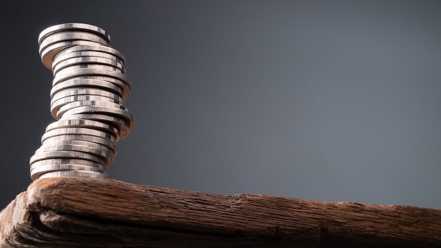 unstable pile of coins at the edge of a table