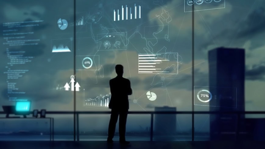 Investor looking out at city skyline with digital symbols around him.