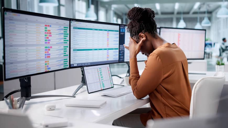 Frustrated woman in front of multiple computer screens