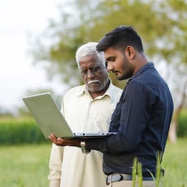 Indian farmer talking with man holding computer