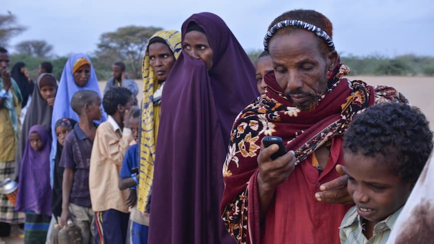 Sahal Gure Mohamed texts on his cell phone while waiting in line at dawn to register at Ifo refugee camp in Dadaab, Kenya.