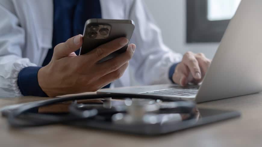 Photo purchased on iStock / no attribution necessary / https://www.istockphoto.com/photo/doctor-using-mobile-smartphone-working-on-laptop-computer-in-medical-office-close-gm2155793304-576587644