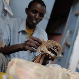 A money exchanger counts Somali shilling notes on the streets of the Somali capital Mogadishu. NextBillion.net